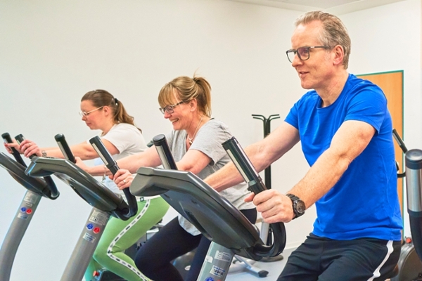 Drei Personen auf einem Ergometer Drei Personen auf einem Ergometer