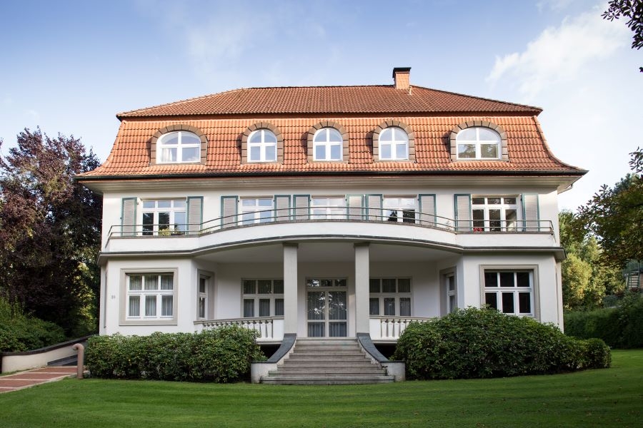 Eine Villa mit Wiese im Vordergrund Eine Villa mit Wiese im Vordergrund